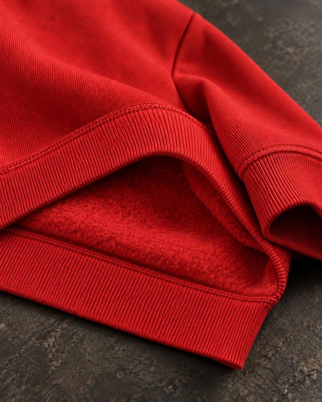 Red sweatshirt hem turned back showing the brushed fleece interior and ribbed cuff